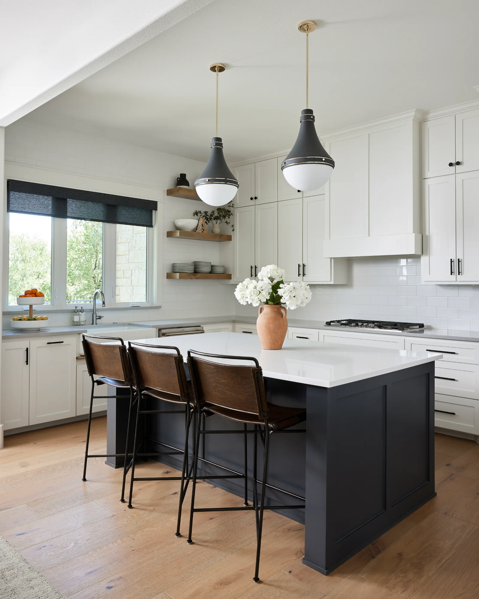 Modern kitchen with black island, pendant lights, and bar stools