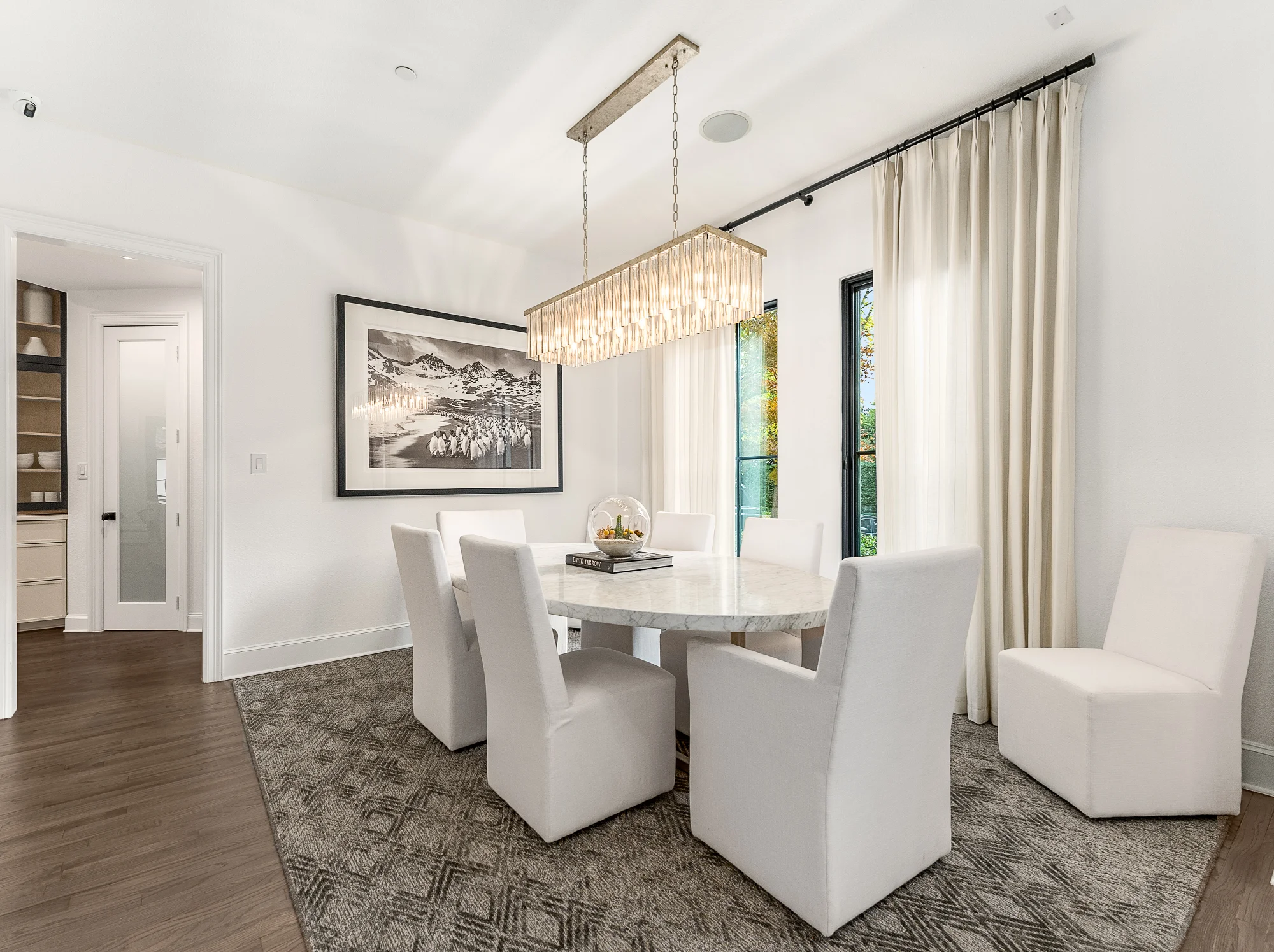 Bright dining room with chandelier and upholstered chairs