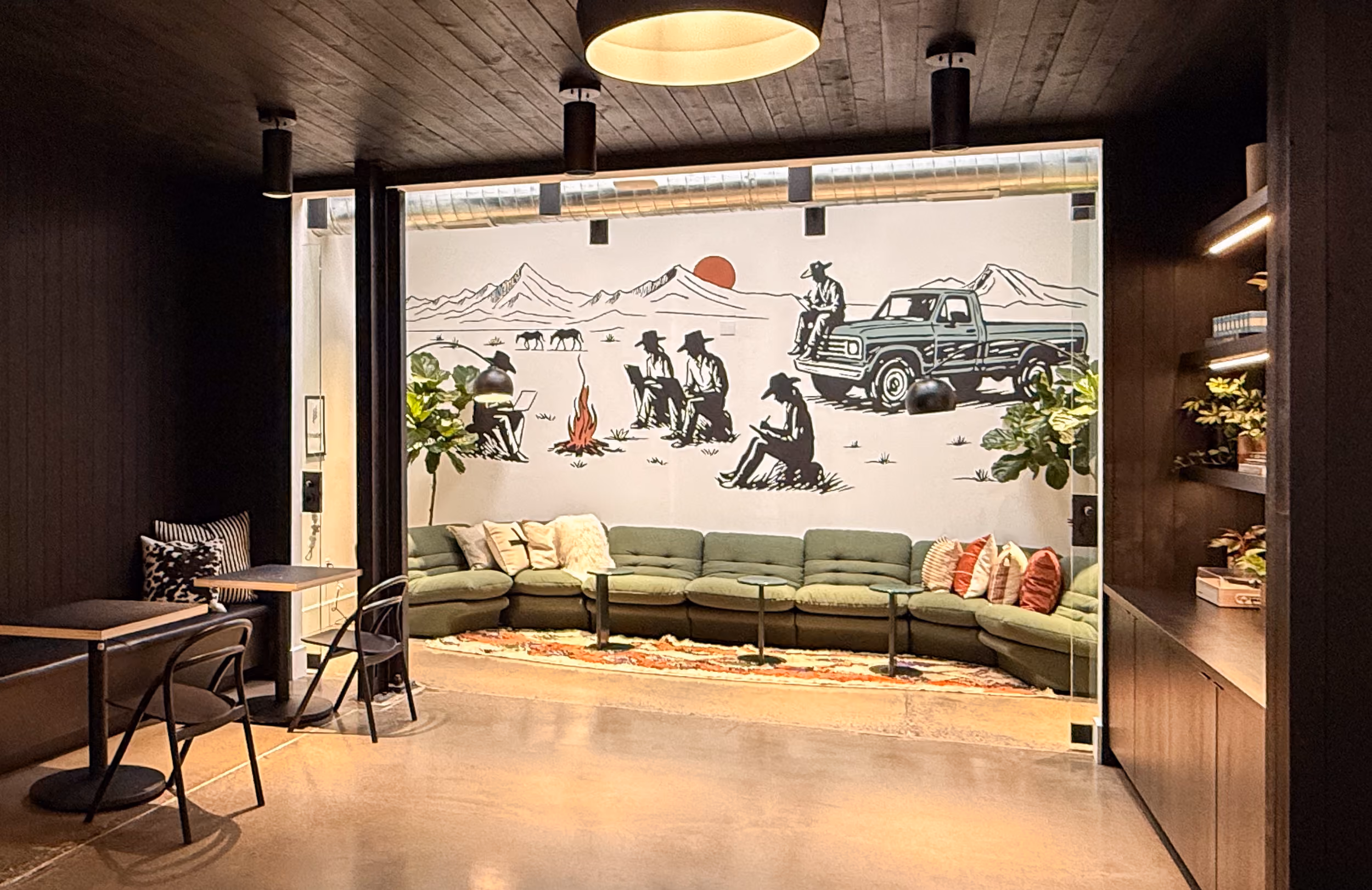 Emberhouse Bozeman HQ featuring a large couch with a mural of cowboys working on maps in the desert