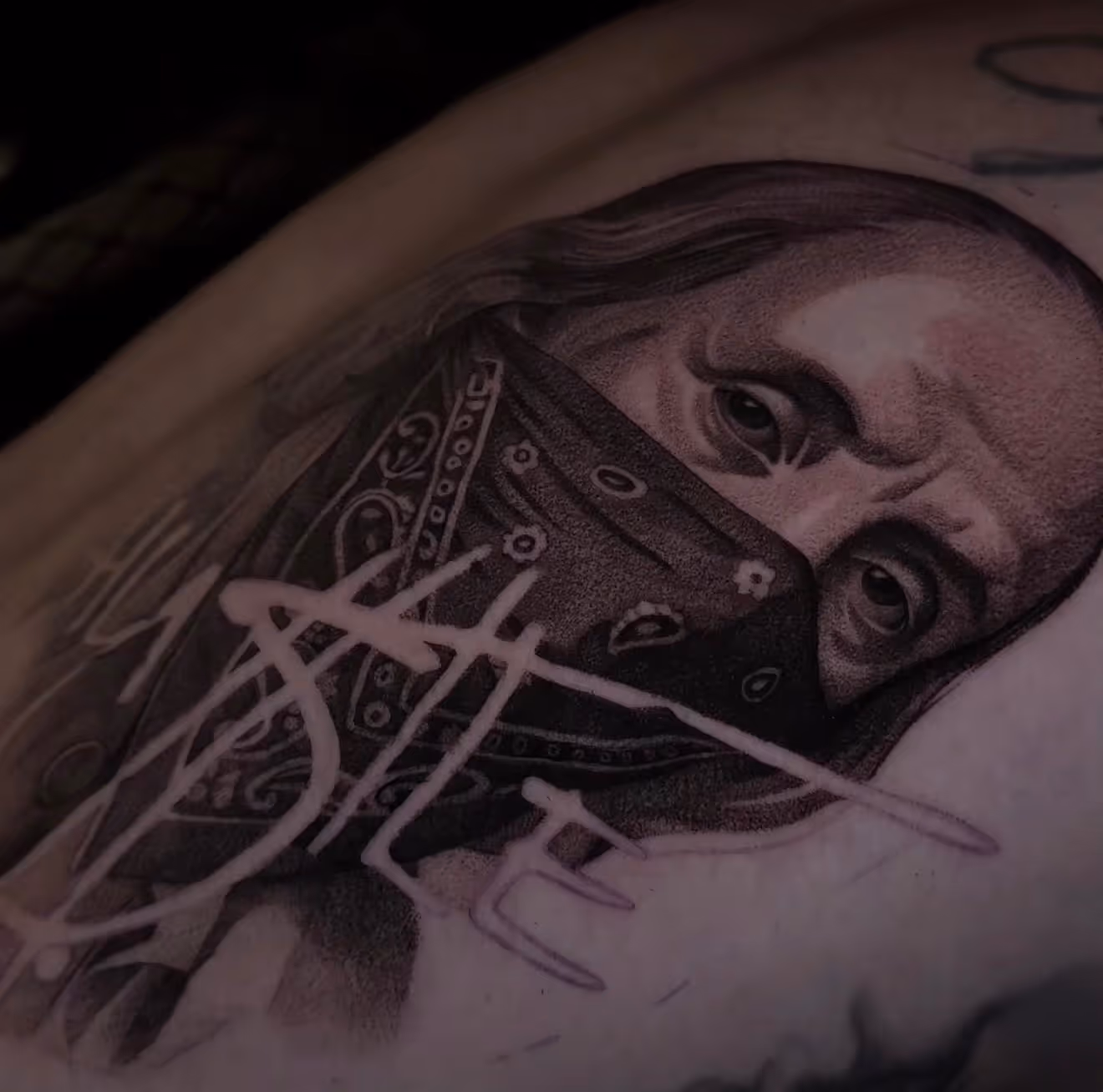 Detailed full sleeve tattoo of a large grinning face with a protruding tongue, a snarling wolf skull, a castle, and a grim reaper skull on a person's arm.