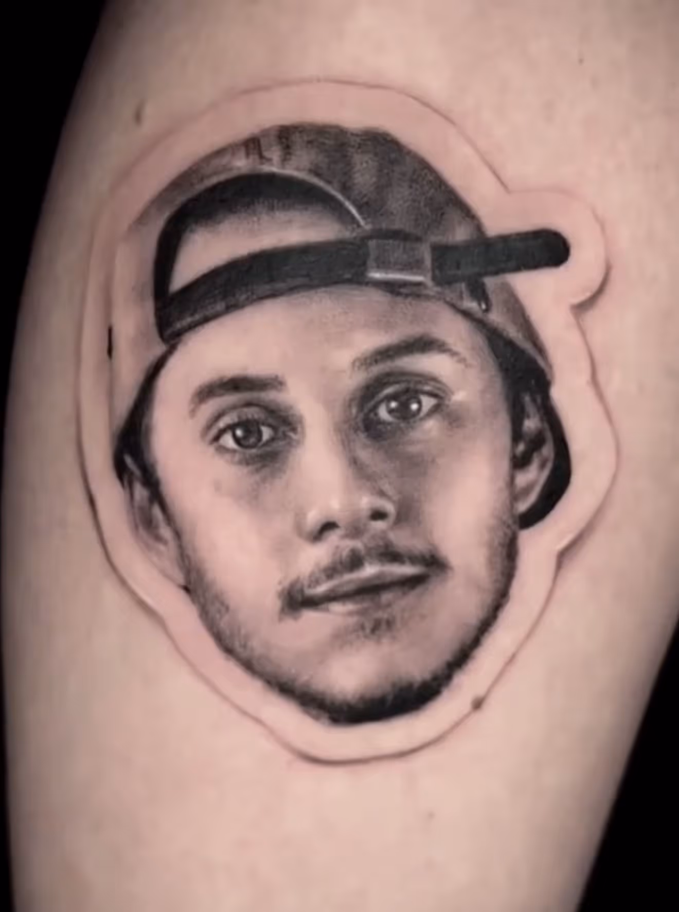 Detailed full sleeve tattoo of a large grinning face with a protruding tongue, a snarling wolf skull, a castle, and a grim reaper skull on a person's arm.