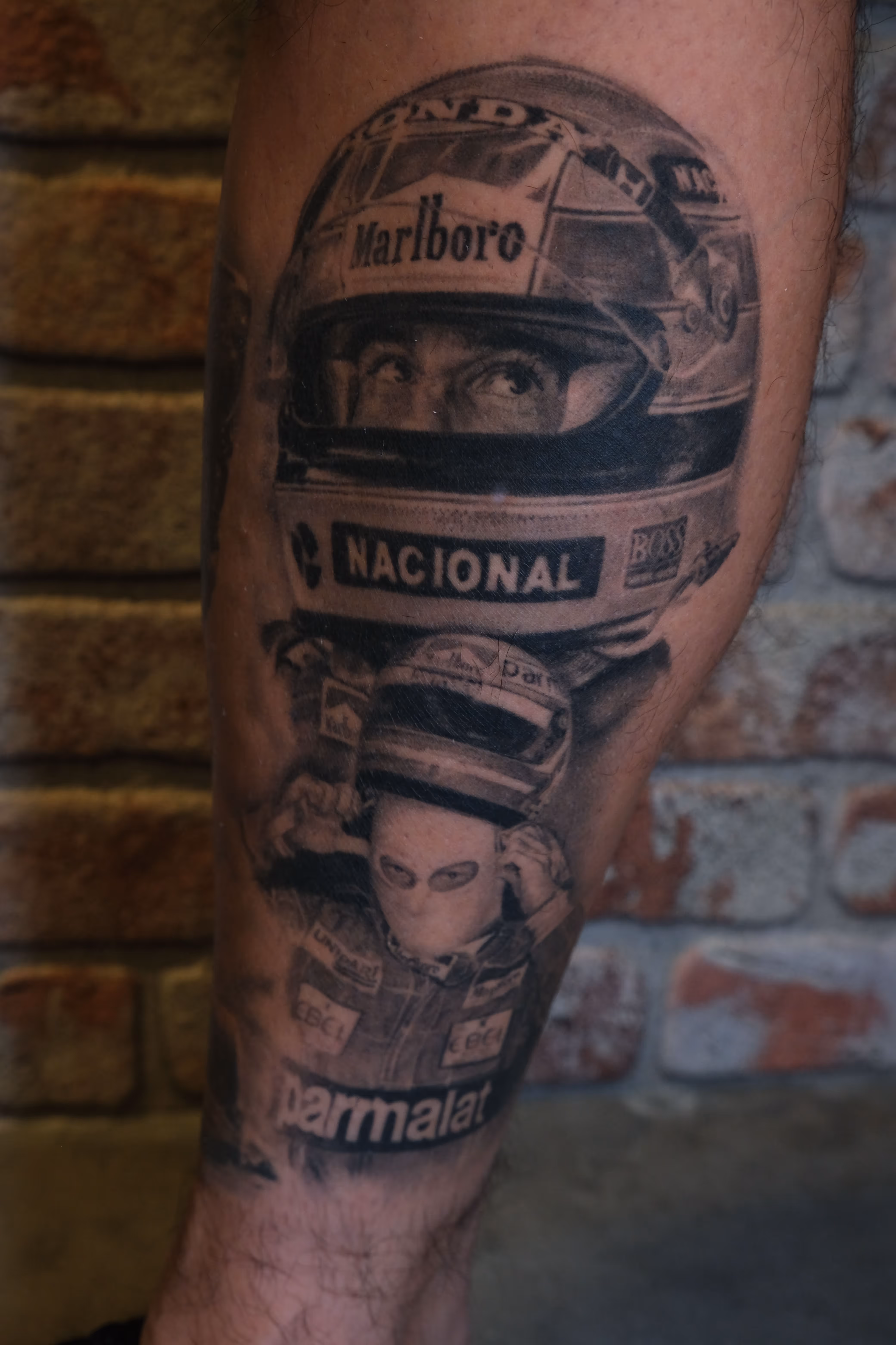 Detailed full sleeve tattoo of a large grinning face with a protruding tongue, a snarling wolf skull, a castle, and a grim reaper skull on a person's arm.