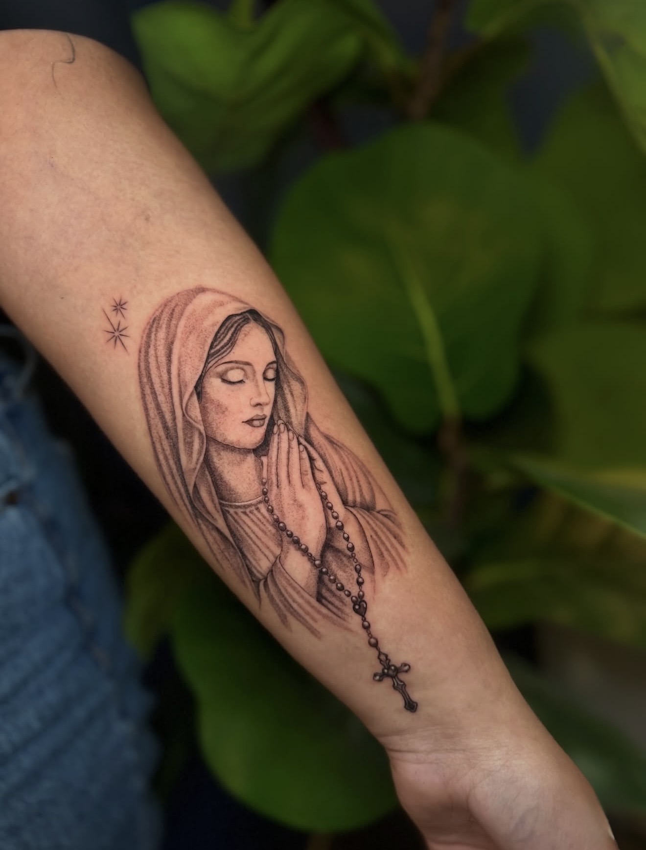 Detailed full sleeve tattoo of a large grinning face with a protruding tongue, a snarling wolf skull, a castle, and a grim reaper skull on a person's arm.