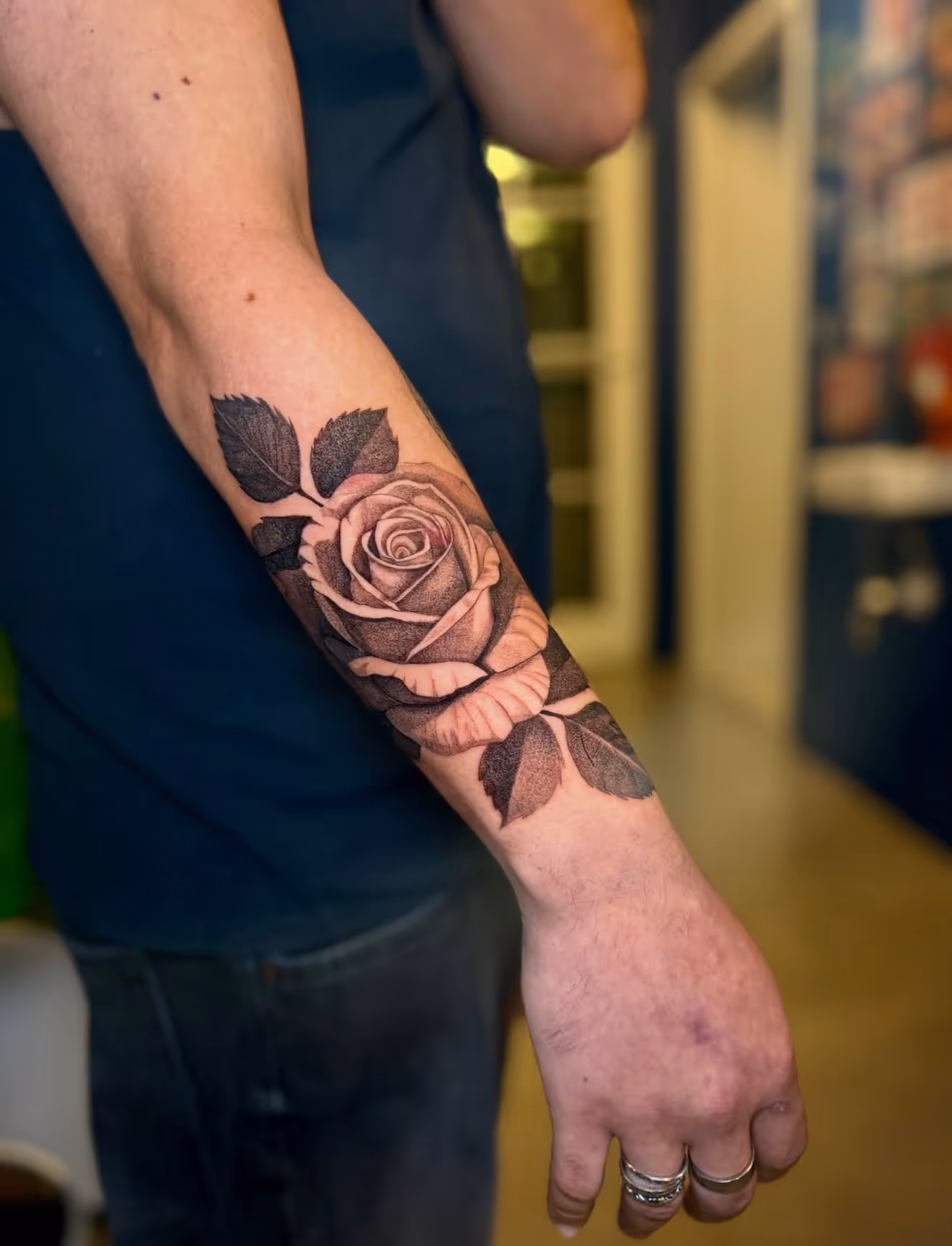 Detailed full sleeve tattoo of a large grinning face with a protruding tongue, a snarling wolf skull, a castle, and a grim reaper skull on a person's arm.