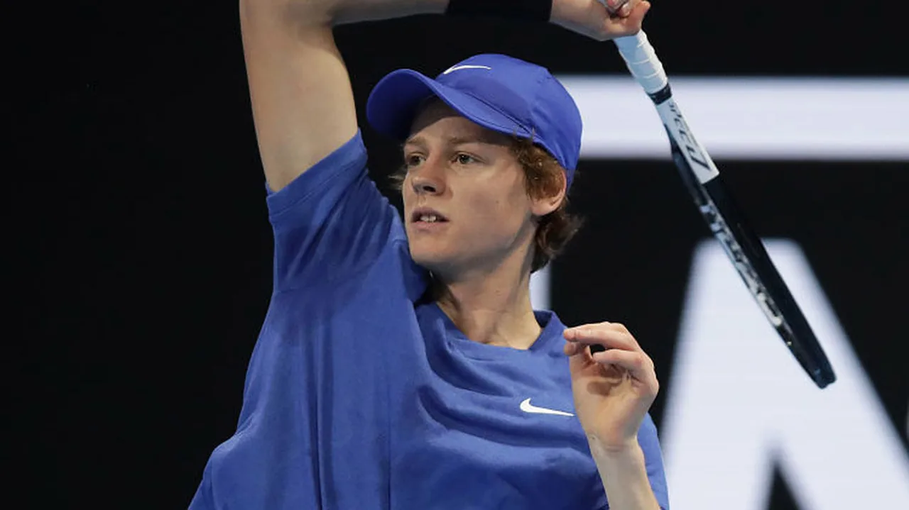 Teenage Jannik Sinner in a blue cap follows through on a forehand on an indoor court