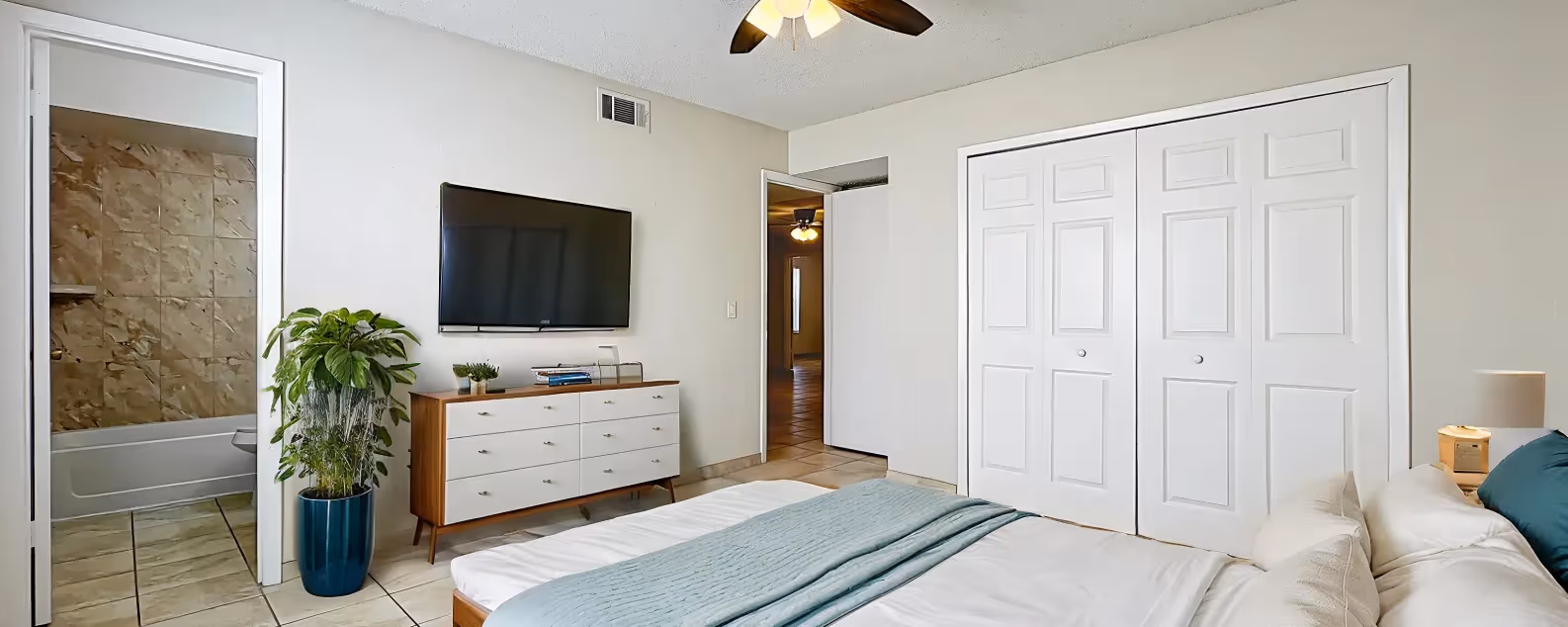 Bedroom with virtually staged furniture including bed, bedside table, tv, and dresser