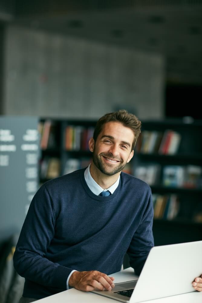 Design, laptop and portrait of business man in office for creative planning or online research. About us, computer and smile with happy designer at desk in workplace for artistic career or job