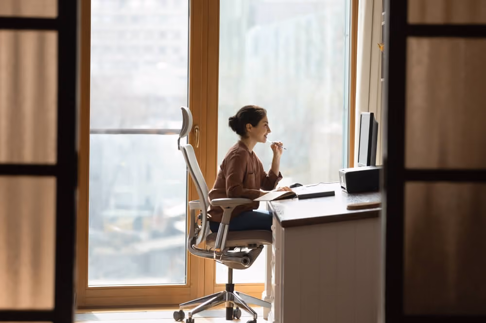 Working at modern home office. Young female architect interior designer sit at desk on ergonomic chair doing job project on desktop pc. Millennial indian woman study at domestic workplace