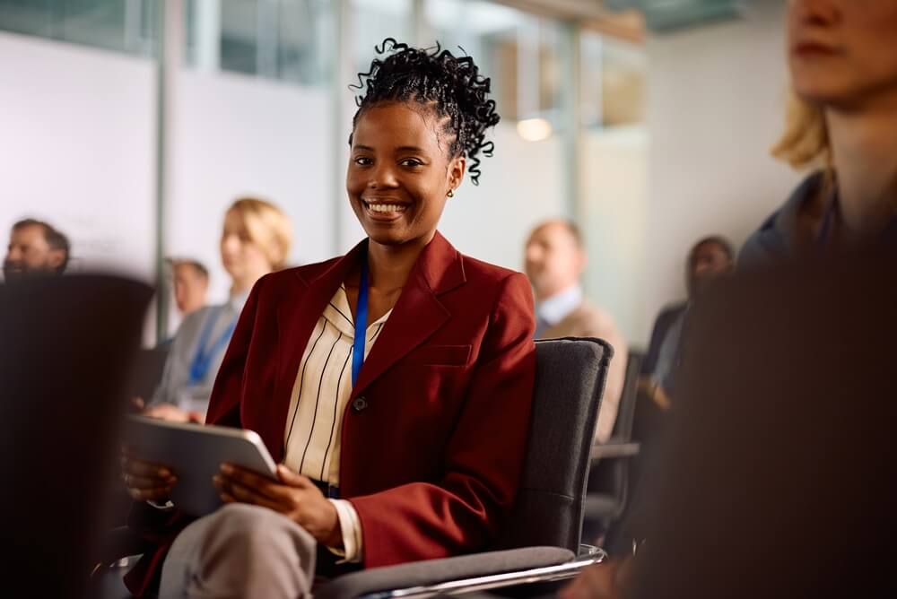Happy African American female entrepreneur attending business conference and looking at camera.