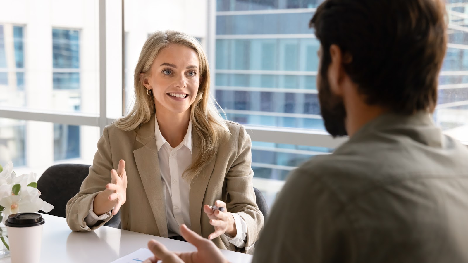 Happy young businesswoman talking with a business partner at an office table
