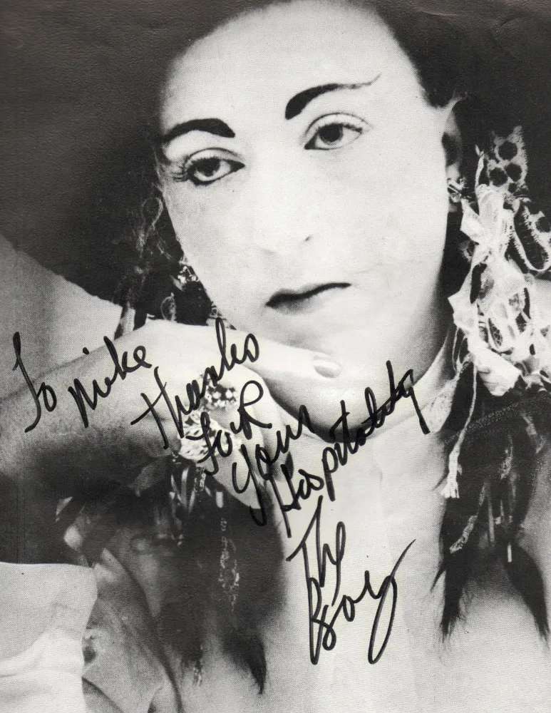 Black and white portrait of a person with distinctive makeup and accessories, with a handwritten message thanking someone for their hospitality.