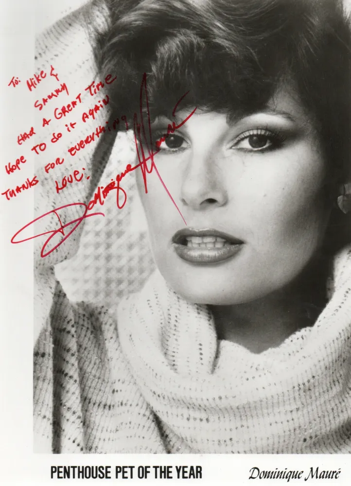 Black and white portrait of Dominique Mauré wearing a knitted sweater with handwritten red autograph, labeled 'Penthouse Pet of the Year'.
