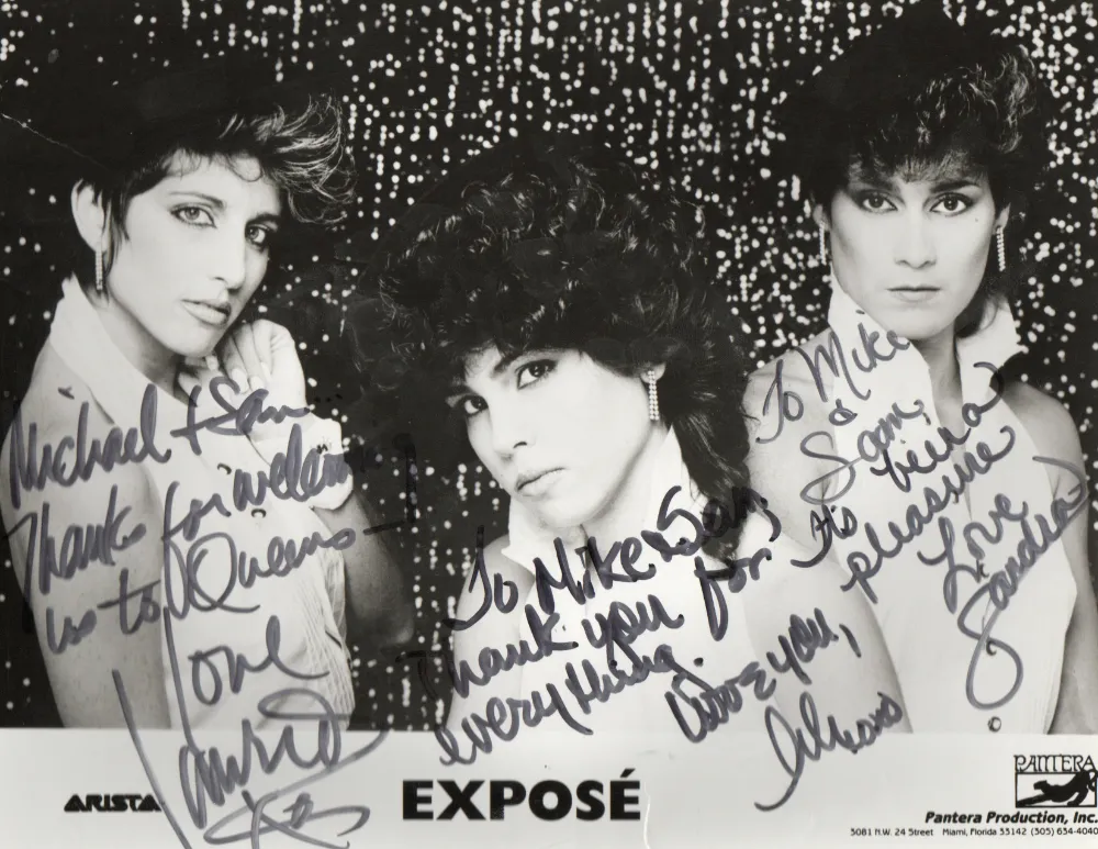 Black and white promotional photo of the music group Exposé with three women posing against a sparkling background, each with handwritten autograph and messages.