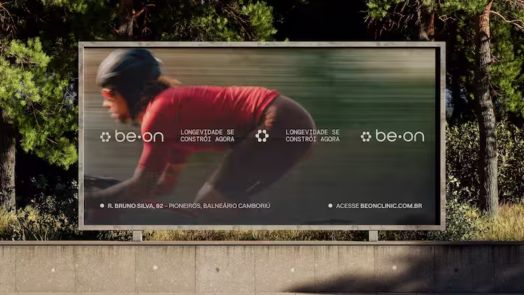 White tote bag with shell illustrations and text 'Nature Inspires You. Always.' hanging on rocky beach by the ocean.