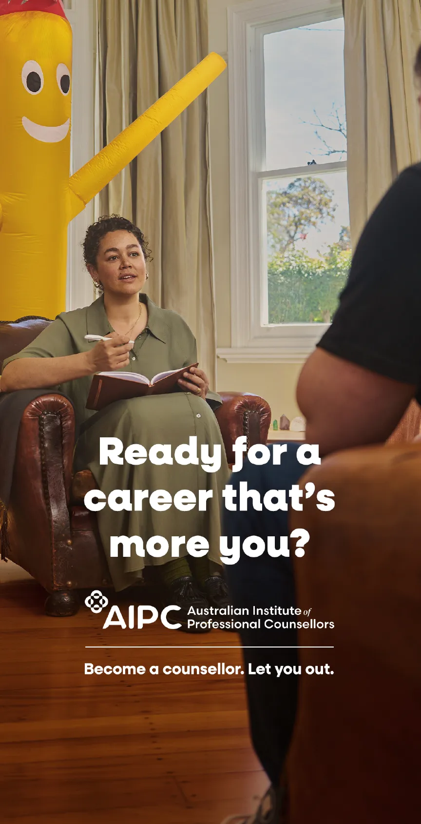 AIPC ad: counselor taking notes in an armchair beside a yellow inflatable tube man. “Ready for a career that’s more you?”