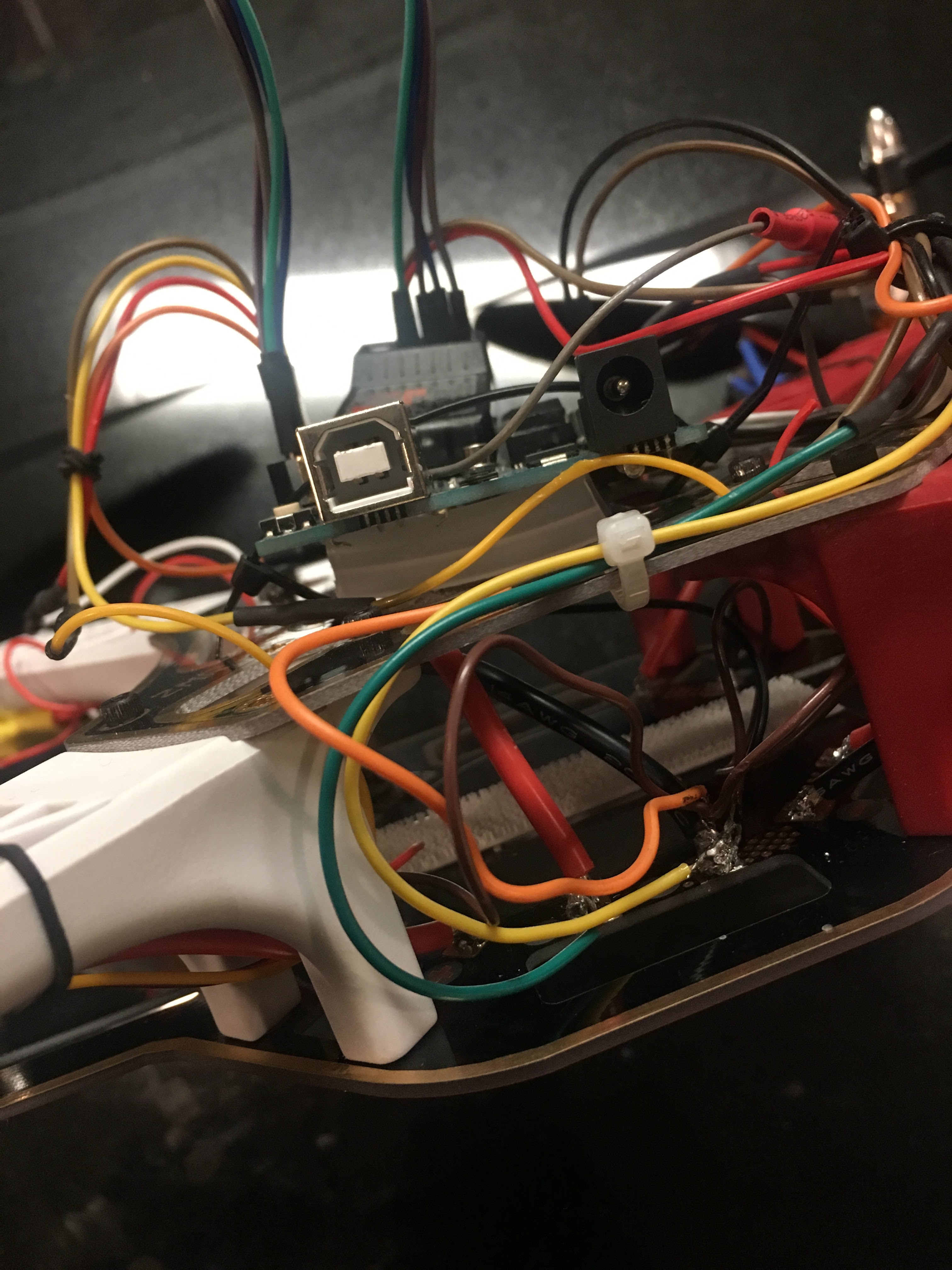 Close-up of a drone's circuit board with various colored wires connected and a USB port visible.