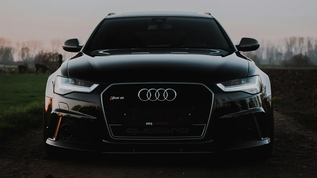 Schwarzer Audi RS 6 Quattro frontal bei Dämmerung auf Landstraße.