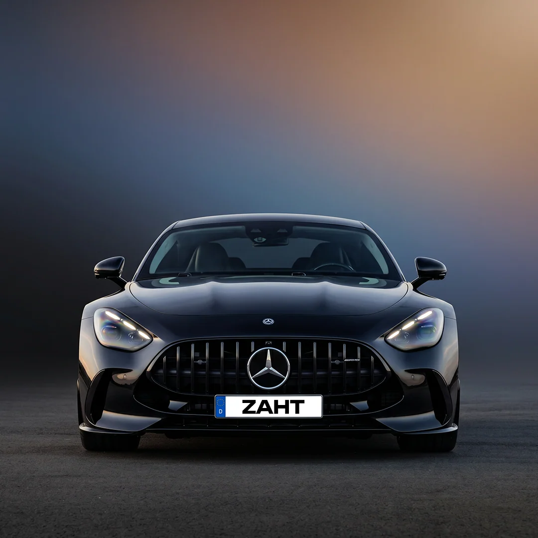 Vorderansicht eines schwarzen Mercedes-AMG-Sportwagens mit beleuchtetem Scheinwerfer und Zahlt-Kennzeichen.