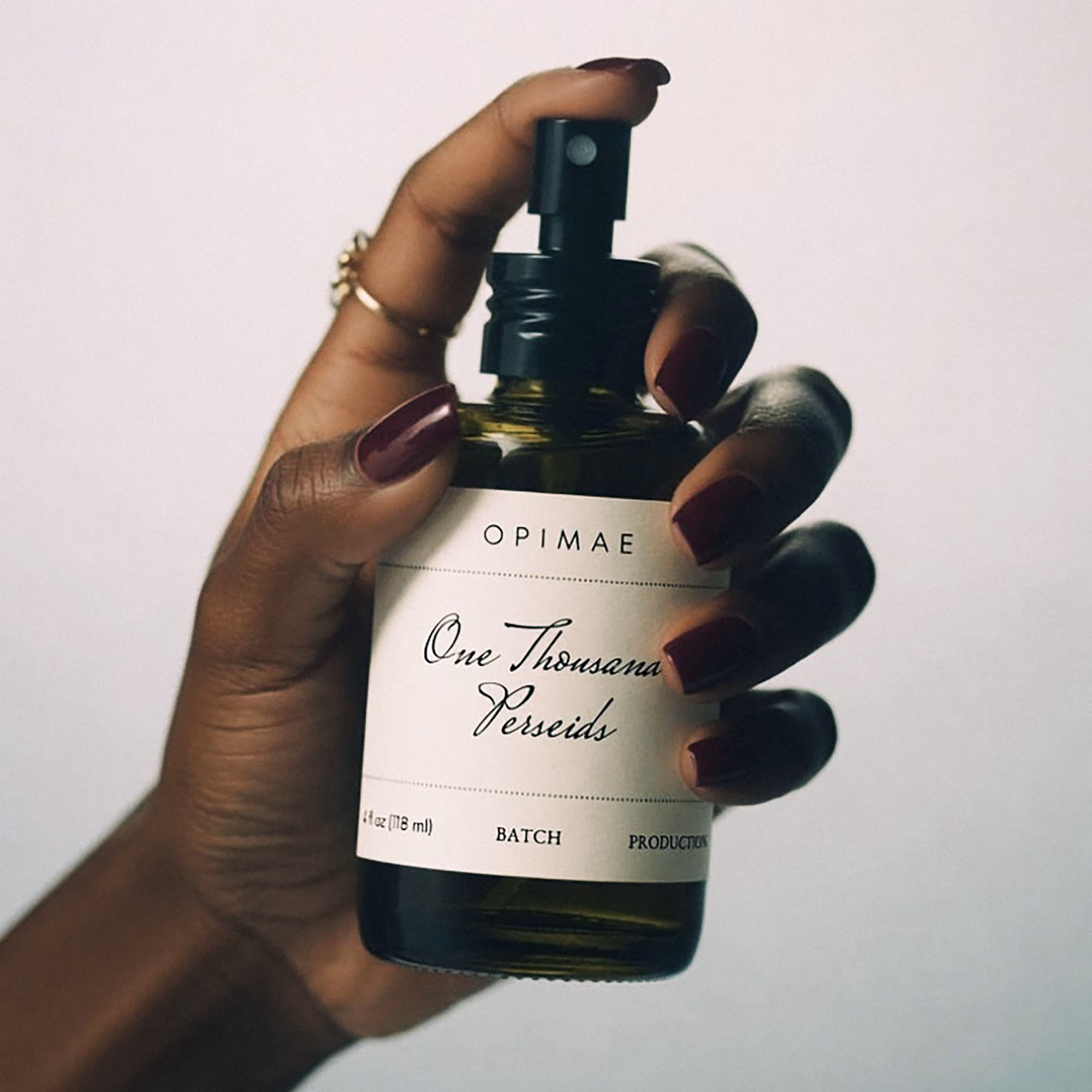 A hand artistically holding a bottle of One Thousand Perseids