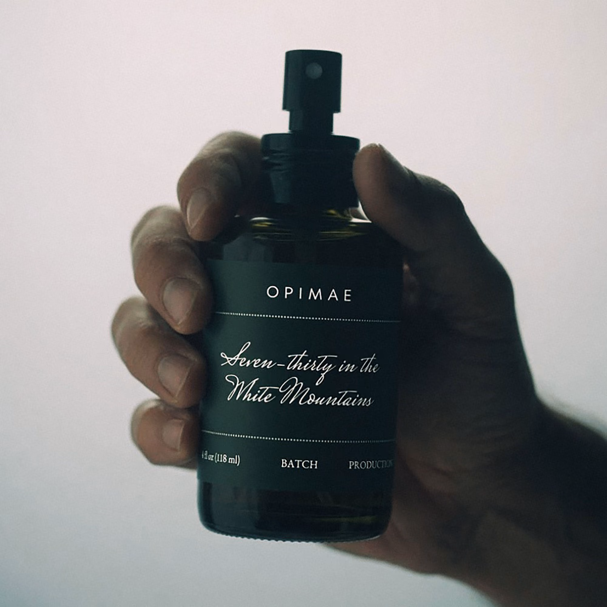 A hand artistically holding a bottle of Seven-thirty in the White Mountains