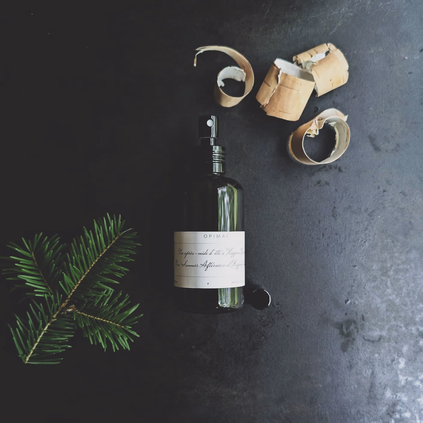 Parfum d'ambiance Opimae entouré de ses ingrédients bruts