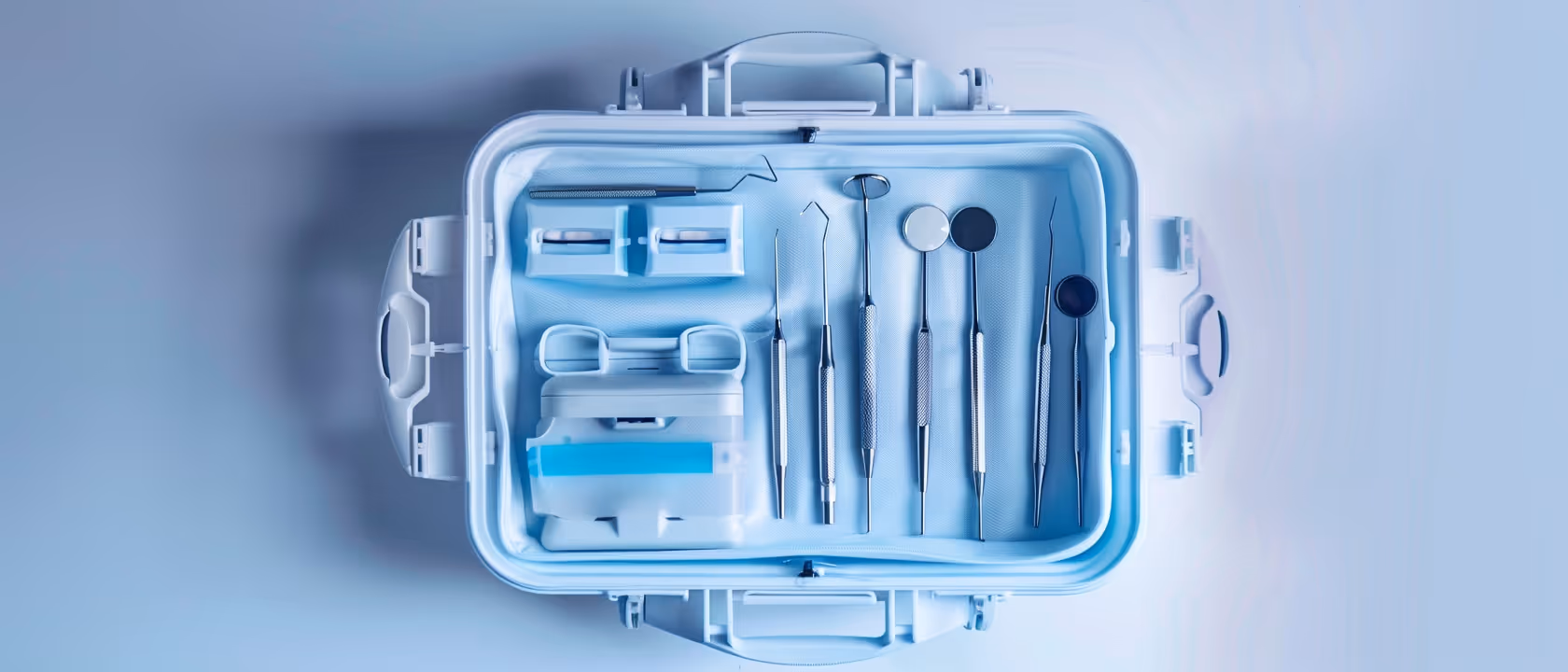 Portable blue case open to show organized dental tools including mirrors and scalers.