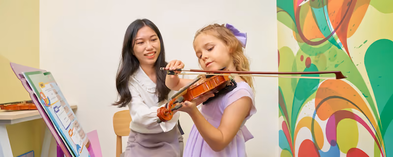 A teacher assisting her student, a young girl, on how to properly hold a violin during a lesson.