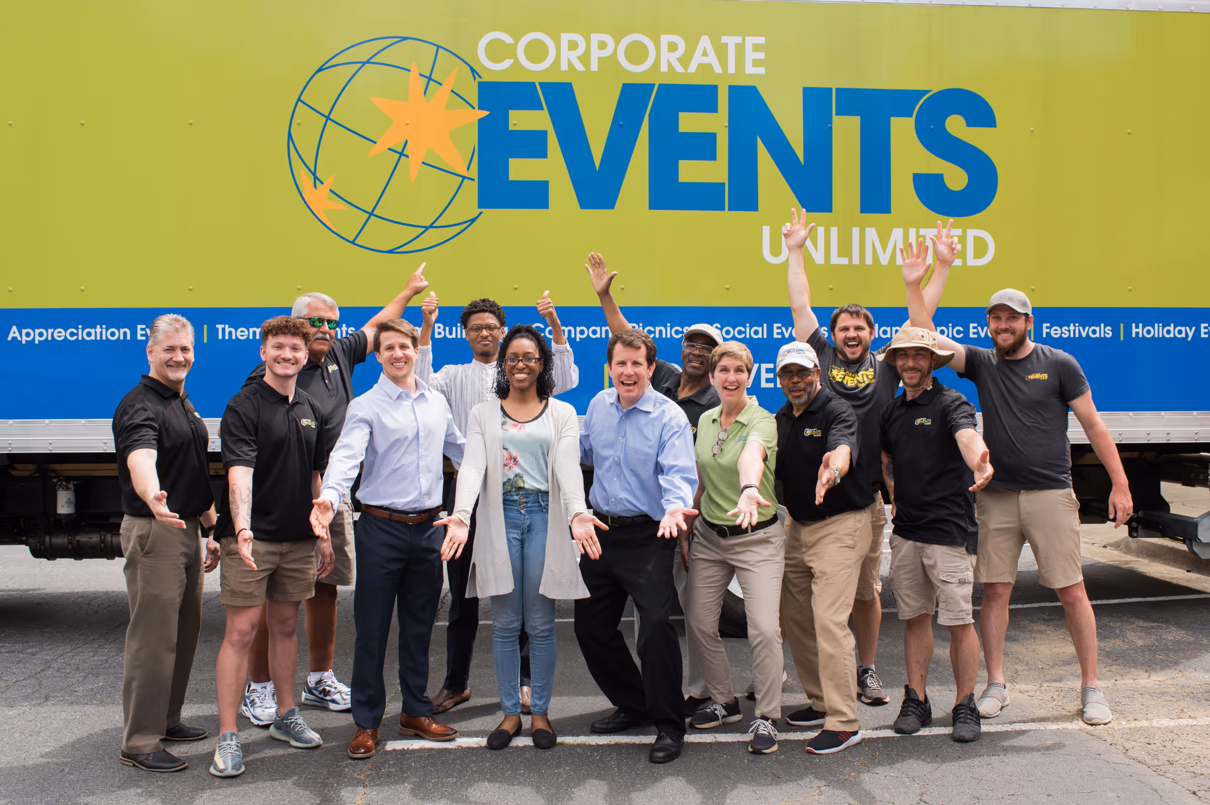 Group of smiling Corporate Events Unlimited staff posing energetically in front of a company truck.