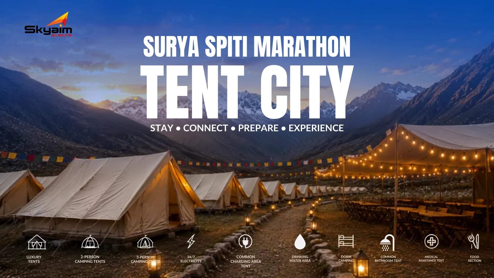 Rows of illuminated beige tents set up in a mountain valley at dusk with string lights overhead.