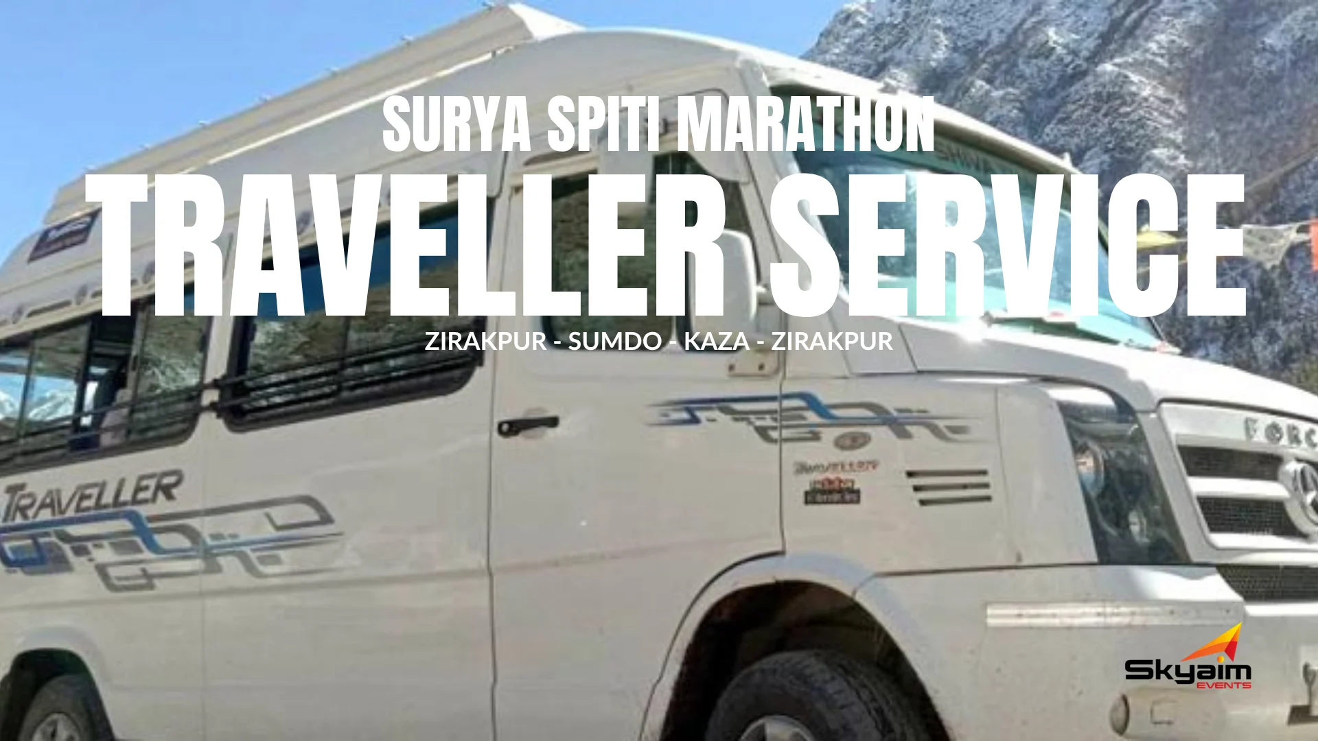 White traveller van parked with mountainous landscape in the background under blue sky.