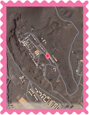 Aerial view of a small settlement with buildings and winding roads in a barren, mountainous area.