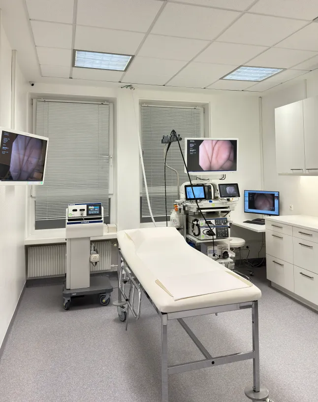 Drei Chirurgen im Operationssaal, die konzentriert eine Operation durchführen, alle tragen OP-Masken und Schutzkleidung.