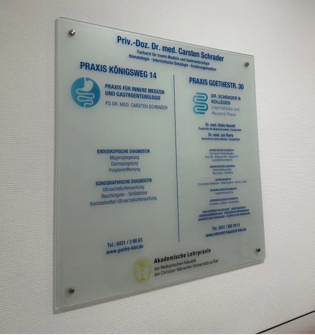 Ein Arzt im weißen Kittel spricht mit einem Patienten, der auf einer Untersuchungsliege in einem modernen medizinischen Behandlungsraum sitzt.