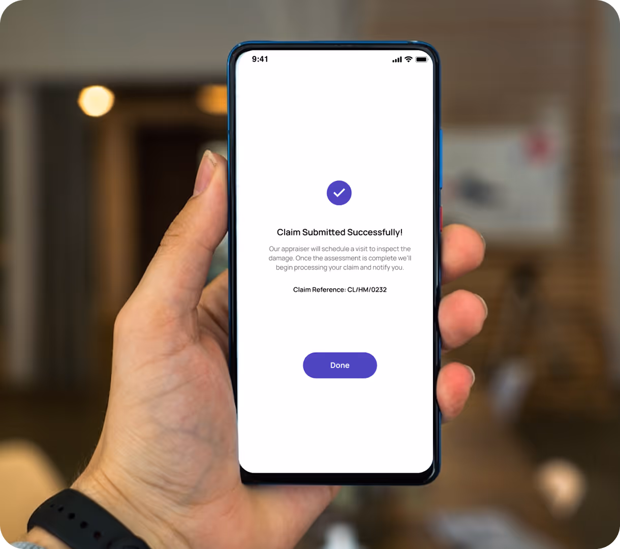Hand holding a smartphone displaying a confirmation screen that a claim was submitted successfully with a Done button.