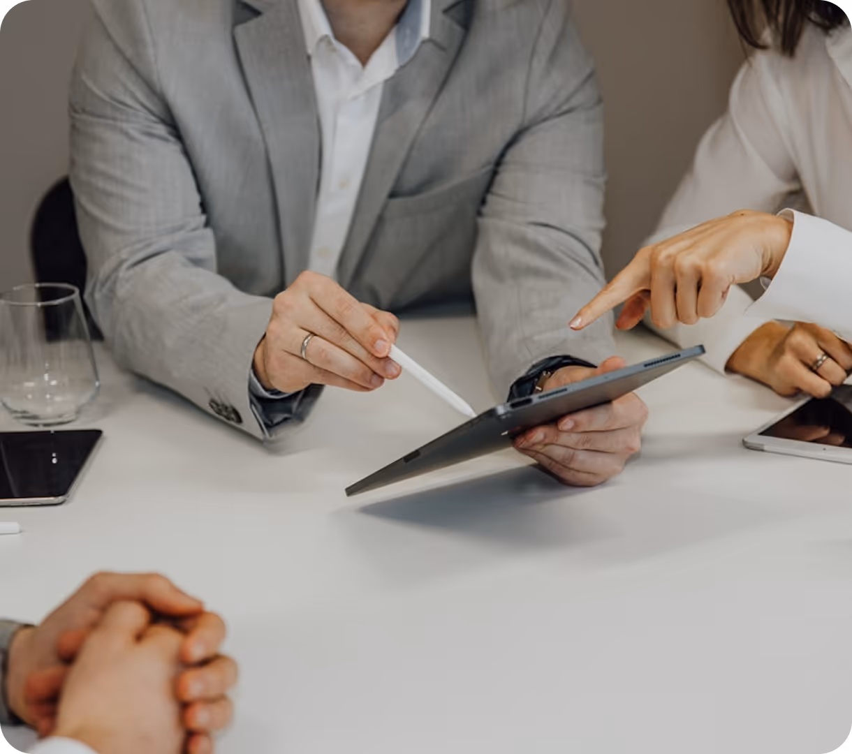 Two people discussing while one holds a tablet and uses a stylus and the other points at the screen in a business meeting setting.