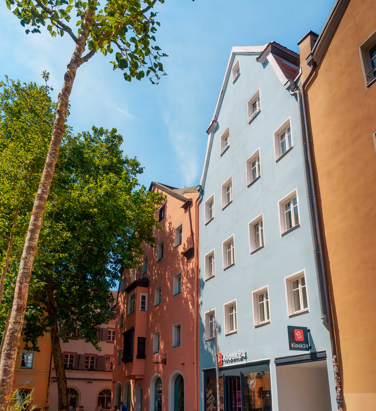 Colorful European buildings with trees and a clear blue sky above on a sunny day.