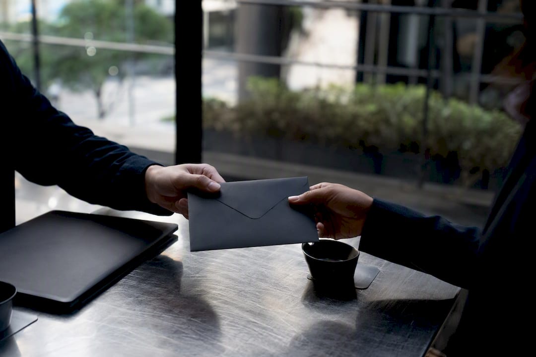 Hands exchanging NDA envelope