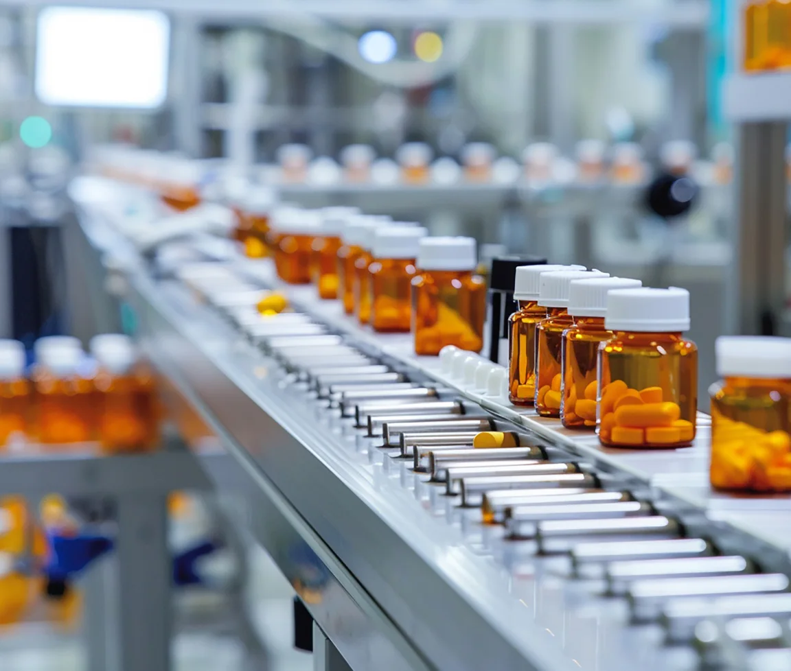 Verschiedene Tablettenflaschen mit weißen Deckeln auf einer Produktionslinie in einer pharmazeutischen Fabrik.