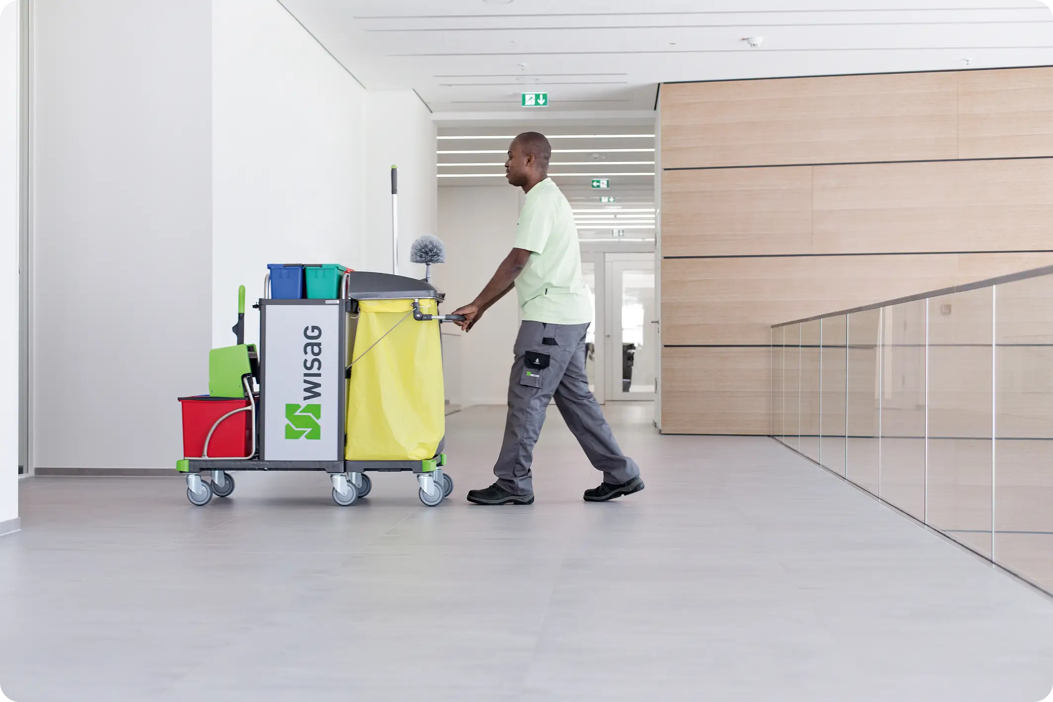 A WISAG member of staff pushing a cart down a modern hallway