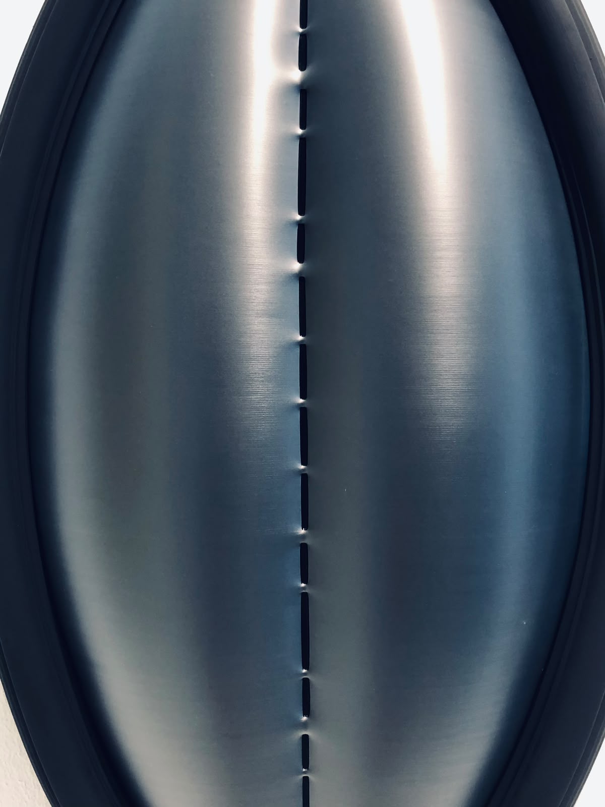 Nahaufnahme einer gebogenen Metallfläche mit einer vertikalen Naht in der Mitte.