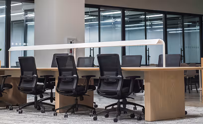 BBC - Salle de réunion moderne avec une grande table en bois clair et plusieurs chaises de bureau noires.