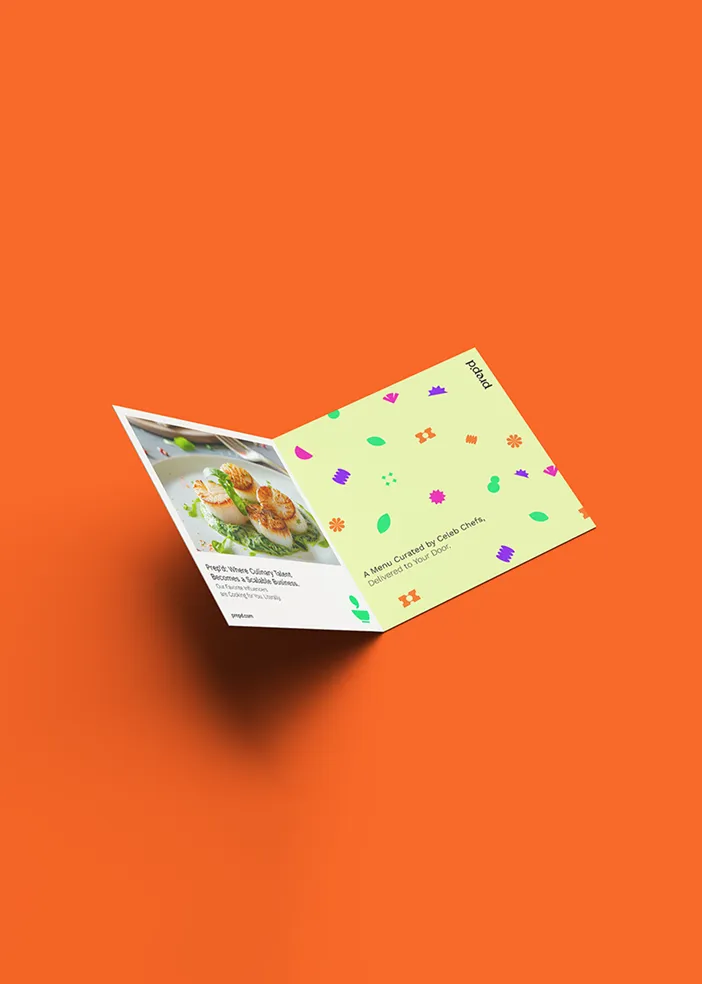 Folded menu with a scallop dish photo and colorful patterns on an orange background.