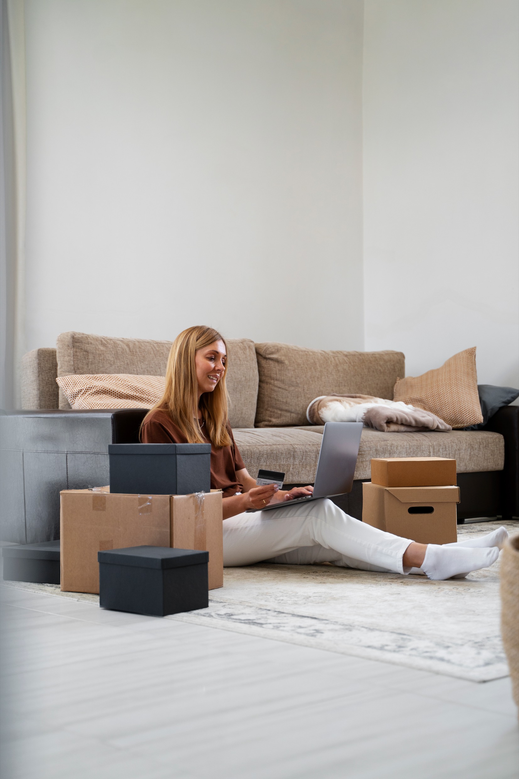 Small business owner packing online orders at home beside a laptop and shipping boxes