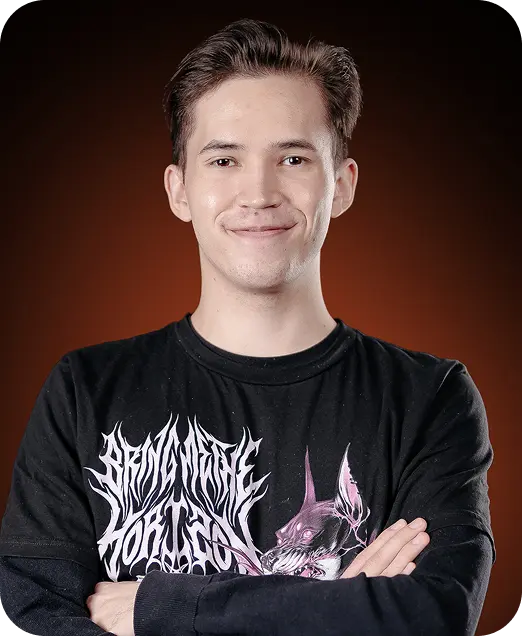 Young man with short brown hair smiling gently, wearing a black graphic t-shirt with crossed arms, brown gradient background.