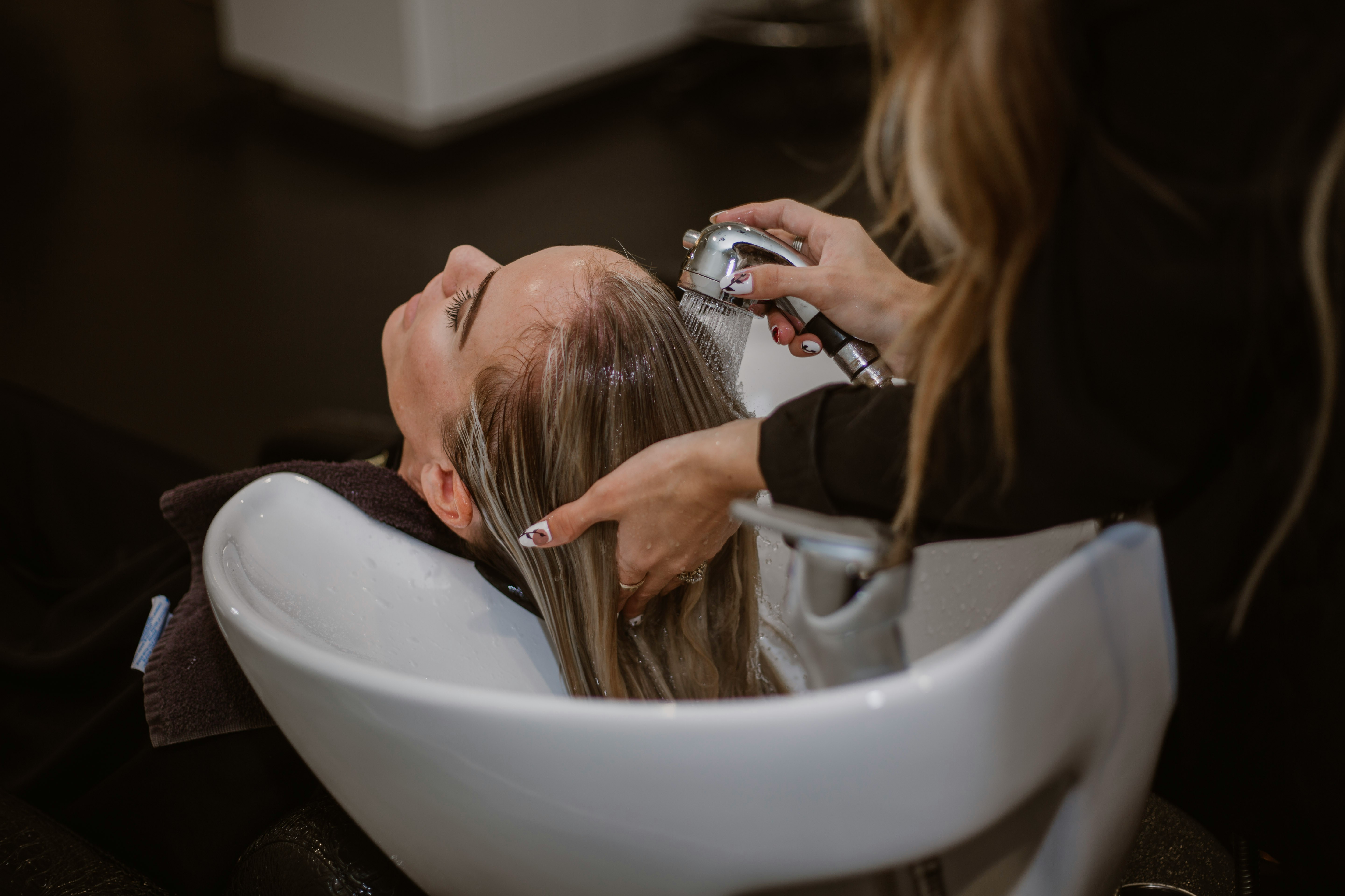A hairdresser washing their clients hair at a basin in a hair salon