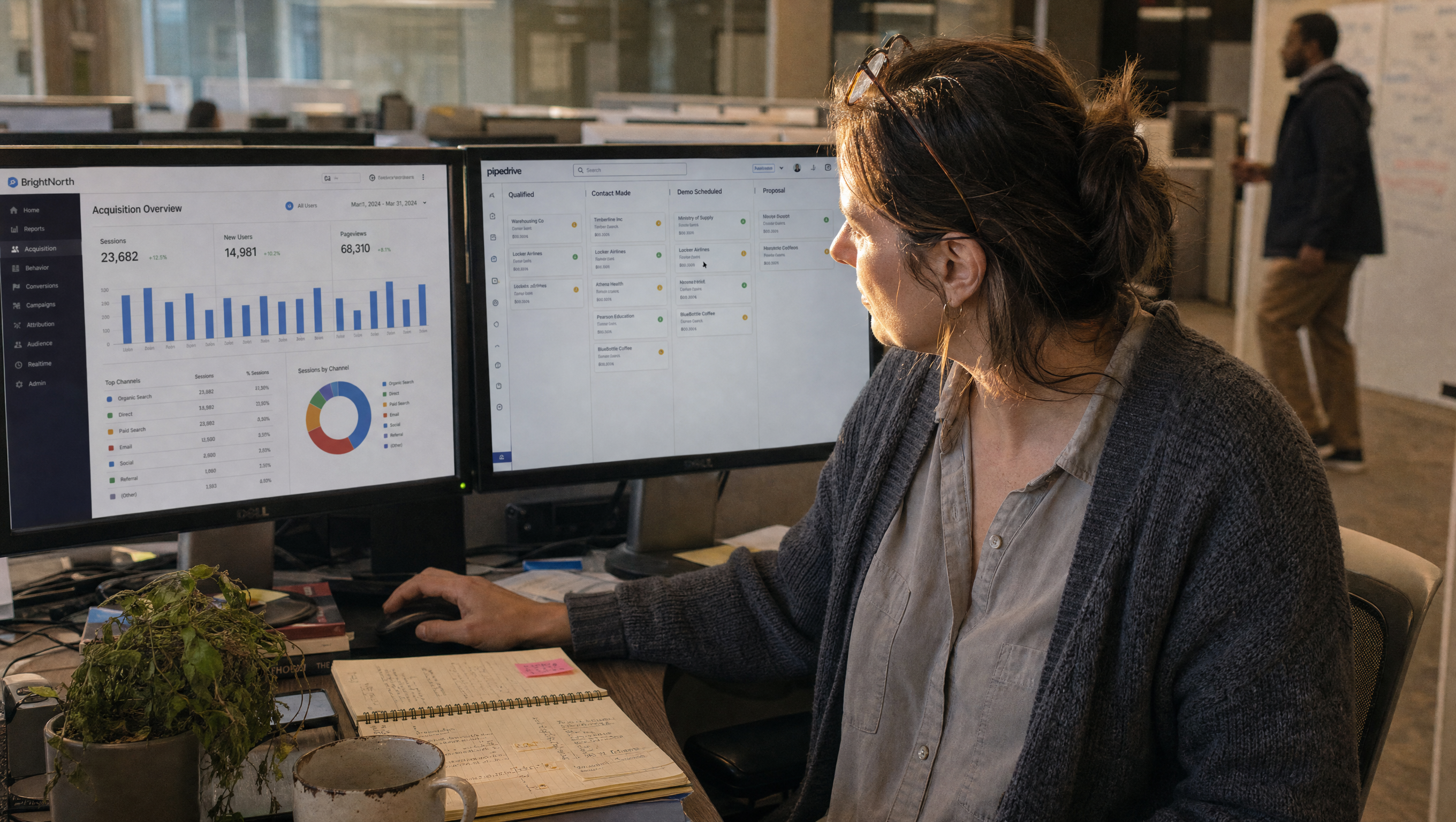A demand-generation manager at her desk reviewing a GA4 acquisition report and a CRM pipeline view