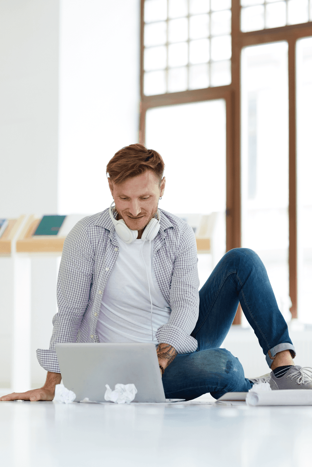 Man sat on the floor working on a laptop.