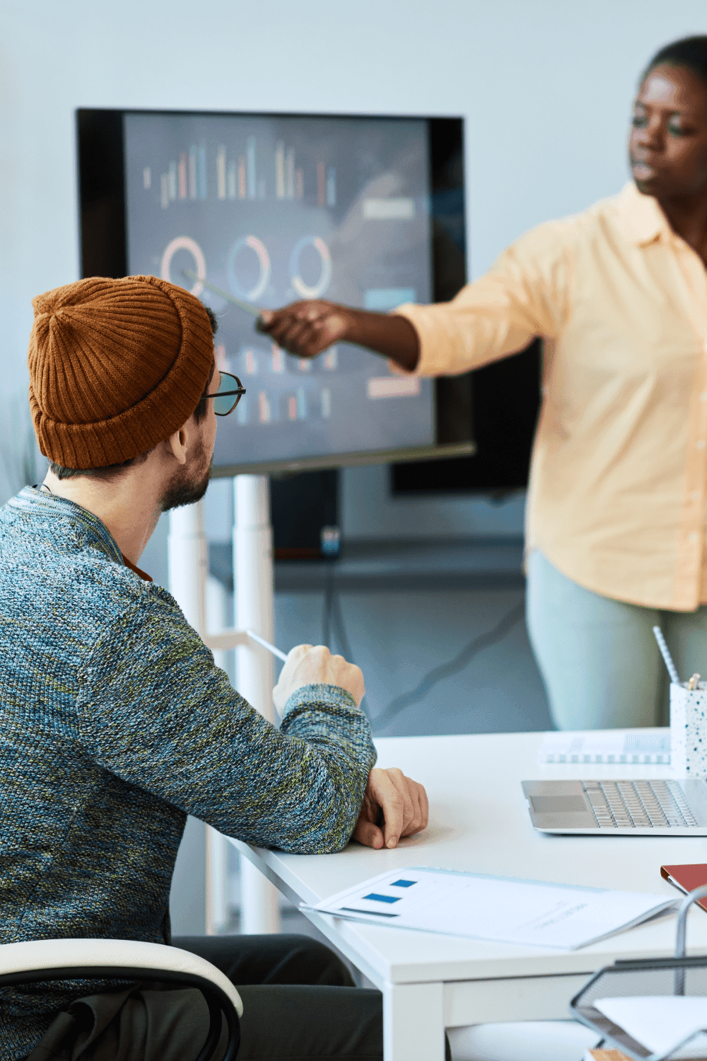 Woman presenting data to a man sitting at a desk.