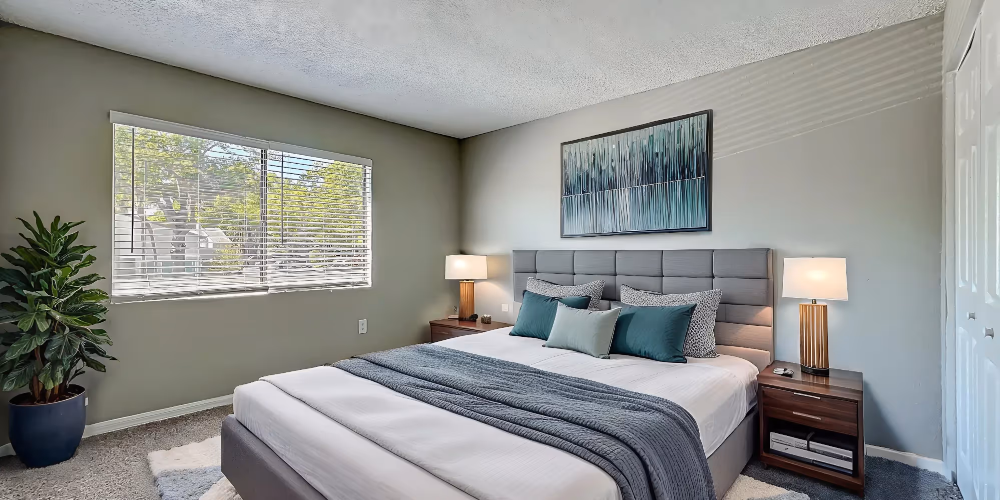 Bedroom with virtually staged furniture including bed, plant, and bedside table with lamp