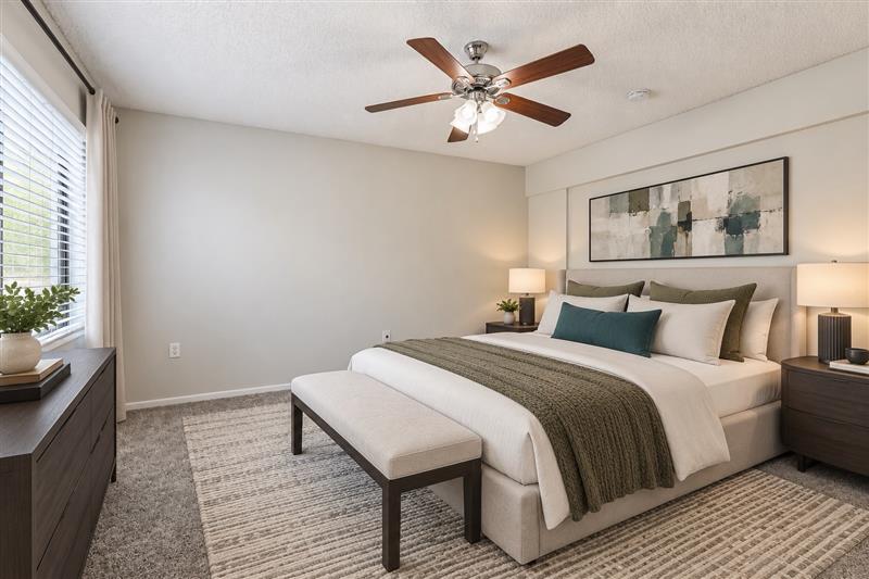 Bedroom with furniture including bed, plant, and bedside table with lamp